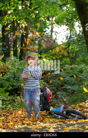 kleiner Junge Autmn Laub wegwerfen Stockfoto