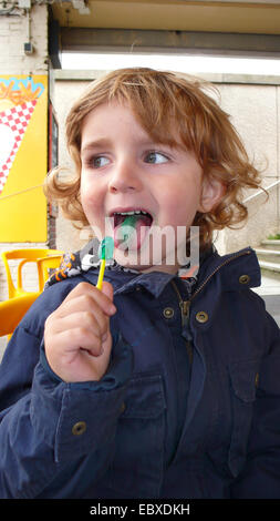 Kleiner Junge mit einer grünen Zunge und eine grüne lolly Stockfoto