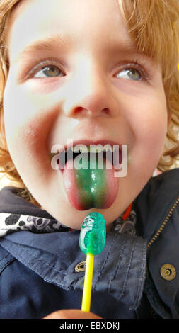 Kleiner Junge mit einer grünen Zunge und eine grüne lolly Stockfoto