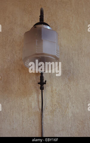 Alte Gaslampe mit Milchglas-Schild auf bemalten grob verputzte Wand montiert mit schmalen Gasleitung Fütterung Mantel Stockfoto