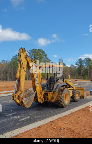 Ein Deere Bagger und Front-Loader geparkt auf eine neue Straße in eine Unterteilung / Immobilien im Bau. Stockfoto