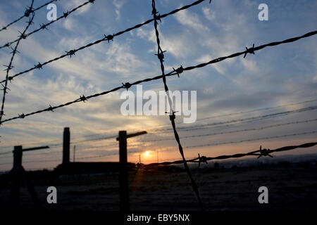 Stacheldraht Zaun des Konzentrationslagers befindet sich gegen den Sonnenuntergang. Stockfoto
