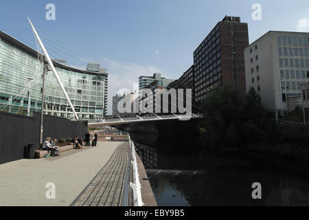 Blick in den blauen Himmel Fluß Irwell und Leute sitzen am Fluss Gehweg Trinity Bridge und Lowry Hotel, Salford, Greater Manchester Stockfoto