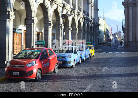 Taxis stehen in Linie entlang der Torbogen des Portal de San Agustin an der Plaza de Armas (Hauptplatz) in Arequipa, Peru Stockfoto