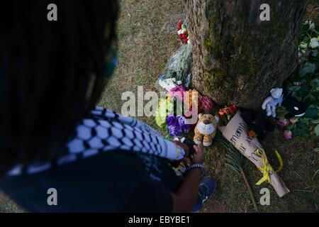 (141205)--JOHANNESBURG, 5. Dezember 2014 (Xinhua)--A Kind schaut das Spielzeug vor Nelson Mandelas Residenz, Johannesburg, Südafrika, am 5. Dezember 2014 gelegt. Menschen gingen bis in die späten Südafrikas Präsident Nelson Mandela Residenz in Houghton wo er verstarb am 5. Dezember 2013, in Johannesburg, Südafrika am Freitag ihr Beileid ausdrücken und zum 1. Jahrestag von Nelson Mandela Tod zu gedenken. (Xinhua/Zhai Jianlan) Stockfoto