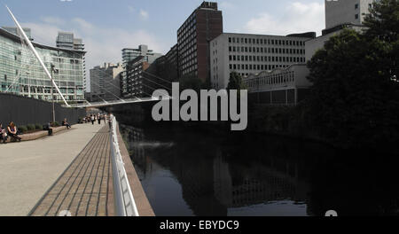 Sonnige Aussicht auf Trinity Bridge und Lowry Hotel, Leute sitzen am Fluss Gehweg von Fluß Irwell Reflexionen, Salford, Manchester Stockfoto