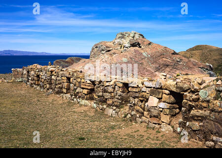 Niedrigen Steinmauer mit Öffnungen neben den Felsen von Puma, der Heilige Rock-Formation auf Isla del Sol im Titicacasee, Bolivien Stockfoto