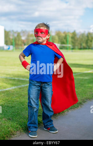 Junge gekleidet in Cape und Maske mit Händen auf den Hüften stehen und blickte in Richtung Stockfoto