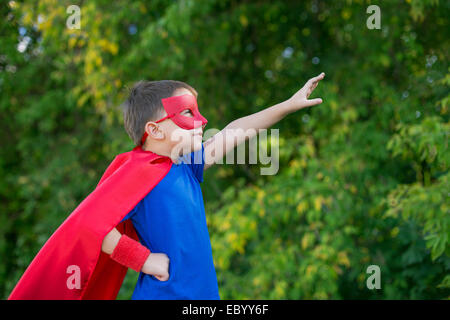 Junge gekleidet in Cape und Maske seitlich stehend und mit der Aufforderung auf weiter Stockfoto