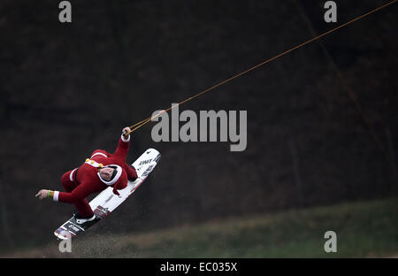 Garbsen, Deutschland. 6. Dezember 2014. Ein Mann verkleidet als Weihnachtsmann über eine Barrikade auf einem Wakeboard auf den Blauer See in Garbsen, Deutschland, 6. Dezember 2014 springt. Foto: ALEXANDER KOERNER/Dpa/Alamy Live News Stockfoto