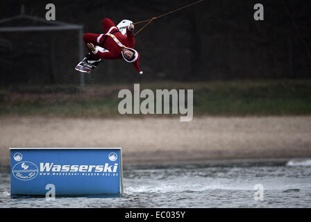 Garbsen, Deutschland. 6. Dezember 2014. Ein Mann verkleidet als Weihnachtsmann über eine Barrikade auf einem Wakeboard auf den Blauer See in Garbsen, Deutschland, 6. Dezember 2014 springt. Foto: ALEXANDER KOERNER/Dpa/Alamy Live News Stockfoto