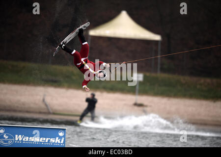 Garbsen, Deutschland. 6. Dezember 2014. Ein Mann verkleidet als Weihnachtsmann über eine Barrikade auf einem Wakeboard auf den Blauer See in Garbsen, Deutschland, 6. Dezember 2014 springt. Foto: ALEXANDER KOERNER/Dpa/Alamy Live News Stockfoto