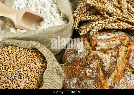 Laib Brot, Mehl, Weizen und Weizen Spike auf Tisch Stockfoto