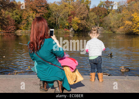 Mutter Einnahme Tochter Foto Fütterung der Enten, Central Park Lake, NYv, USA Stockfoto