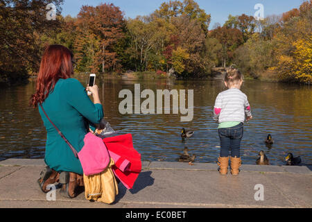 Mutter Einnahme Tochter Foto Fütterung der Enten, Central Park Lake, NYv, USA Stockfoto