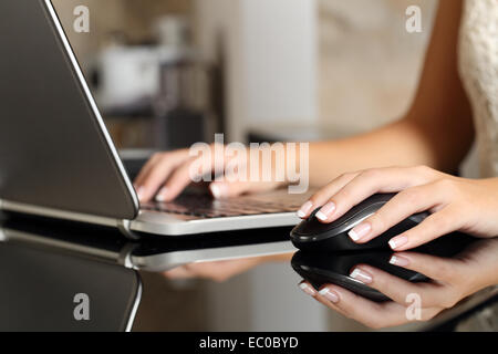 Nahaufnahme einer Frau Hände arbeiten mit einem Laptop und einer Maus in einem Wohngebäude oder einem Büro Stockfoto