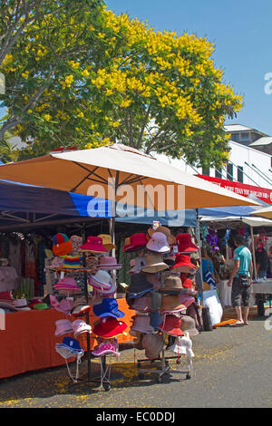 Bunte Hüte zum Verkauf unter Sonnensegels & Blütenbaum am Stand am Wochenmarkt in der Stadt von Maryborough Queensland Stockfoto