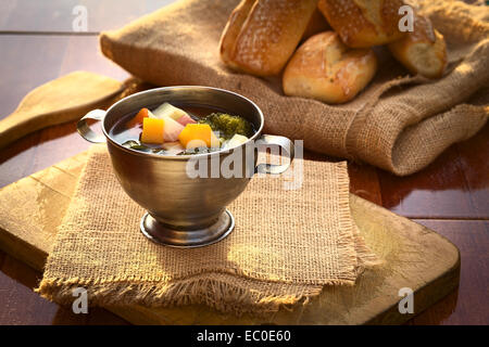 Frische vegetarische Suppe aus Brokkoli, Kürbis, Zwiebel, Möhre, Kartoffel und Tomate serviert in einer Metallpfanne auf Jute-Stoff Stockfoto