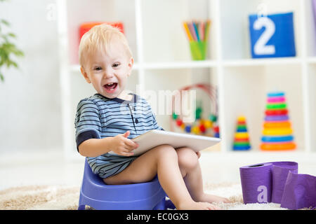 Kind sitzt auf Nachttopf TabletPC spielen Stockfoto