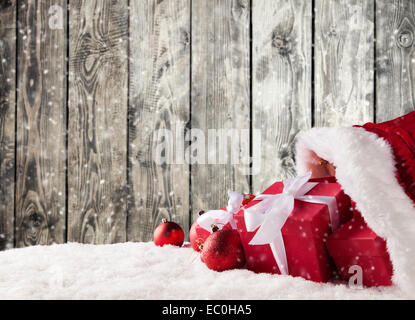 Santa Claus Tasche voller Geschenke auf Schnee. Holzbohlen als Hintergrund Stockfoto