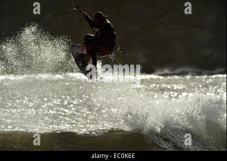 Kite-Surfer im Spray Silhouette wie er hoch über die Welle auf Gower, Wales, UK fliegt.  Ideal für Wind und Wassersport. Stockfoto