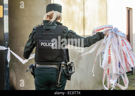 Belfast, Nordirland. 7. Dezember 2014. Ein Polizist entfernt Cordon Band Credit: Stephen Barnes/Alamy Live News Stockfoto