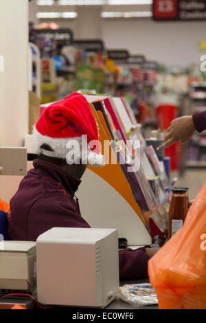 Wimbledon London, UK. 7. Dezember 2014. Mitarbeiter bei einer Sainsburys Supermarkt Filiale auskommen in Weihnachtsstimmung mit Weihnachtsmann Santa hüten Credit: Amer Ghazzal/Alamy Live-Nachrichten Stockfoto