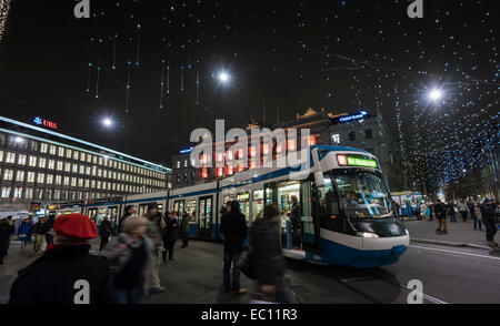 Weihnachts-Einkäufer rund um Zürich Tram Bahn am Zürcher Paradeplatz unter festliche Weihnachtsbeleuchtung. Stockfoto