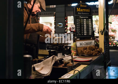 Ein Mann in seiner Kabine ist heiße Kastanien ("Marroni") verkauft an Weihnachts-Einkäufer in der Nacht an der Zürcher Bahnhofstrasse. Stockfoto