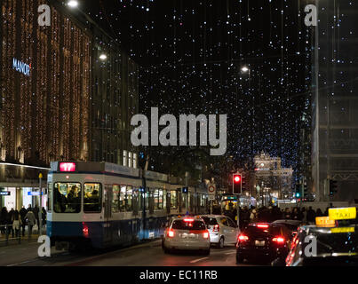 Weihnachts-Einkäufer, Autos und Straßenbahn-Zügen im Zürcher überfüllt Bahnhofstrasse unter der glühenden Weihnachtsbeleuchtung Stockfoto