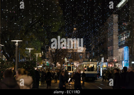 Weihnachts-Einkäufer und Straßenbahn-Zügen im Zürcher überfüllt Bahnhofstrasse unter der glühenden Weihnachtsbeleuchtung Stockfoto