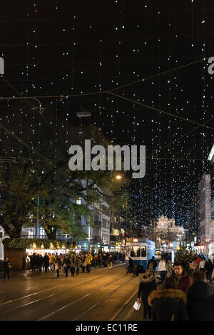 Weihnachts-Einkäufer und Straßenbahn-Zügen im Zürcher überfüllt Bahnhofstrasse unter der glühenden Weihnachtsbeleuchtung Stockfoto