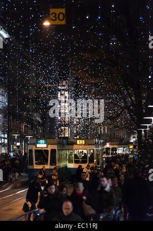 Weihnachts-Einkäufer und Straßenbahn-Zügen im Zürcher überfüllt Bahnhofstrasse unter der glühenden Weihnachtsbeleuchtung Stockfoto