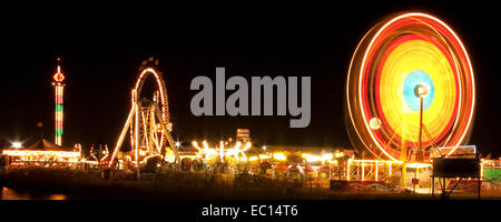 Nacht erschossen von einem Spinnrad Ferris und beleuchtete Fahrten auf einer Kirmes. Stockfoto