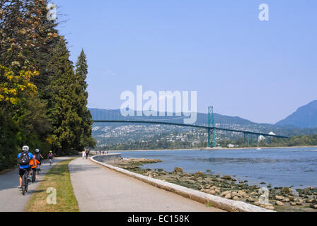 Radfahrer und Fußgänger im Stanley Park mit Lions Gate Bridge im Hintergrund Stockfoto