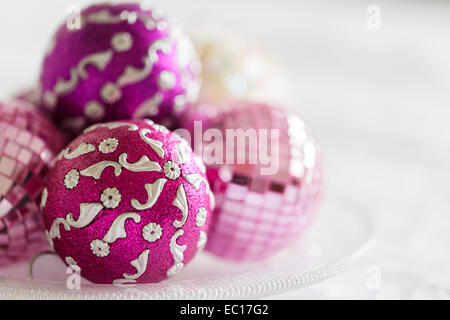 Rosa und lila Weihnachtsschmuck auf einer Glasplatte Stockfoto