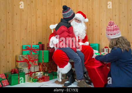 Kinder besuchen Santa in seiner Grotte von Weihnachten Stockfoto