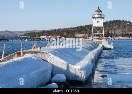 Grand Marais, Minnesota, USA. der gefrorenen Bucht und Leuchtturm mit Eis am See Felsen und der Hafenmauer. Stockfoto