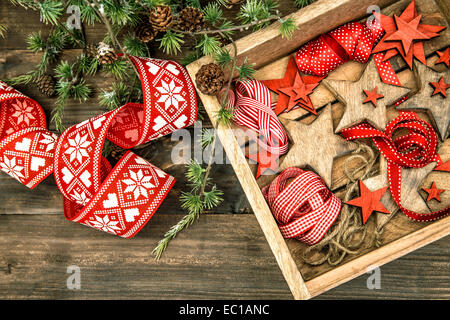 Weihnachtssterne Dekorationen aus Holz und roten Bändern mit Tannenzweigen Baum auf rustikalen hölzernen Hintergrund Stockfoto