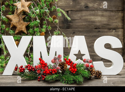 Weihnachtsschmuck und Buchstaben XMAS mit Tannenzweigen Baum auf rustikalen hölzernen Hintergrund Stockfoto