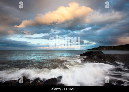 Sonnendurchflutetes Regenwolken über Greymare Rock bei Dämmerung Dunstanburgh Northumberland Küste England Stockfoto