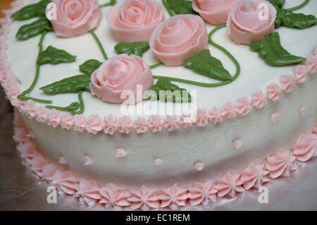 Detail eines Kuchens mit Sahnehäubchen, Zuckerguss Blumen und Blätter. Stockfoto