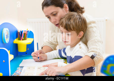 Mutter hilft ihrem Kind, Zeichnungen zu machen Stockfoto