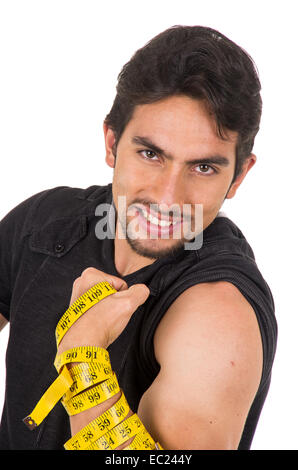 hübscher lächelnde junge Latin Mann zeigt Muskeln umwickelt Maßband Stockfoto