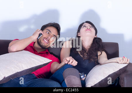 gelangweilt vor dem Fernseher während Freund Freundin chattet am Telefon Stockfoto