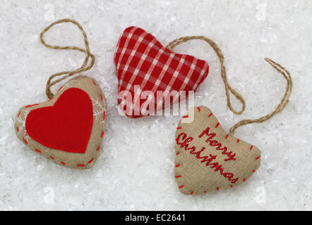 Frohe Weihnachten Karte mit drei roten Herzen auf Schnee Stockfoto