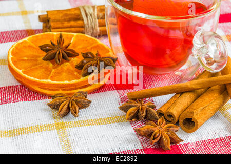 ein paar Anis Sterne, Cassia-Zimt-Sticks, getrocknete orange Ringe und Früchtetee auf der Tischdecke Stockfoto