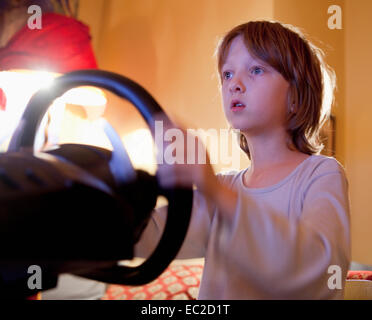 Jungen spielen Konsole Rennspiel mit Lenkrad Stockfoto