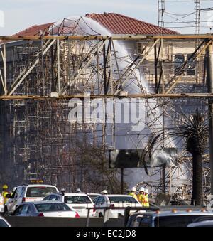 Los Angeles, Kalifornien, USA. 8. Dezember 2014. Feuerwehr Spritzwasser auf Hotspots nach einem massiven Brand entlang State Route 110, die eine Baustelle Mehrfamilienhaus nahe der Innenstadt von Los Angeles, Montag, 8. Dezember 2014 verschlungen. © Ringo Chiu/ZUMA Draht/Alamy Live-Nachrichten Stockfoto