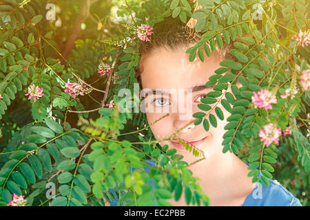 Porträt eines schönen Mädchens in einem blühenden Strauch Stockfoto